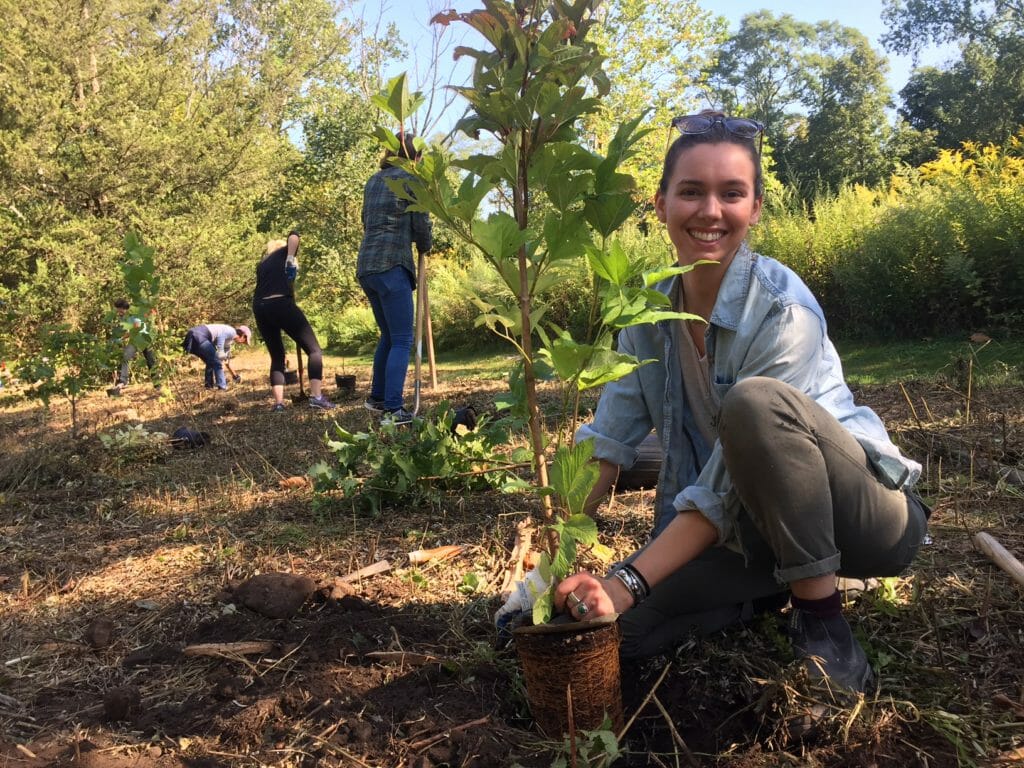person smiling while planting trees.